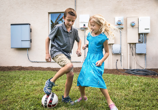 Kids playing in front of battery system and solar inverter