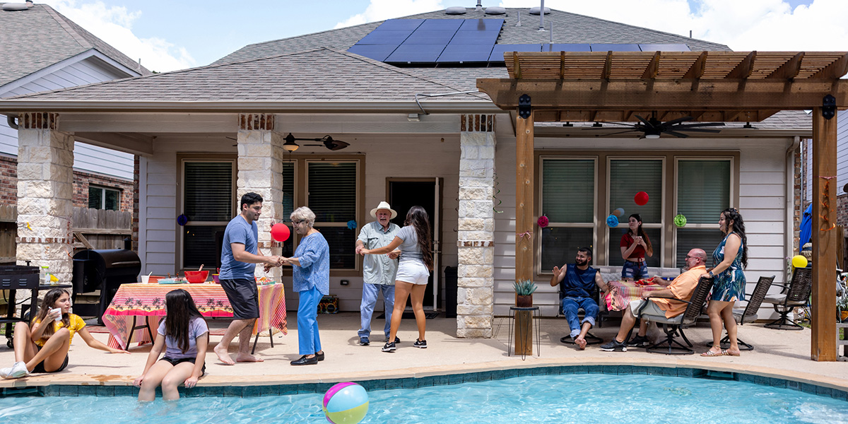 Family pool party in backyard of solar home