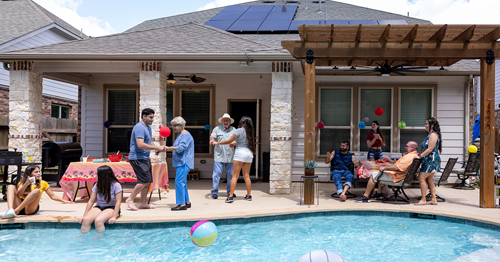 Family pool party in backyard of solar home