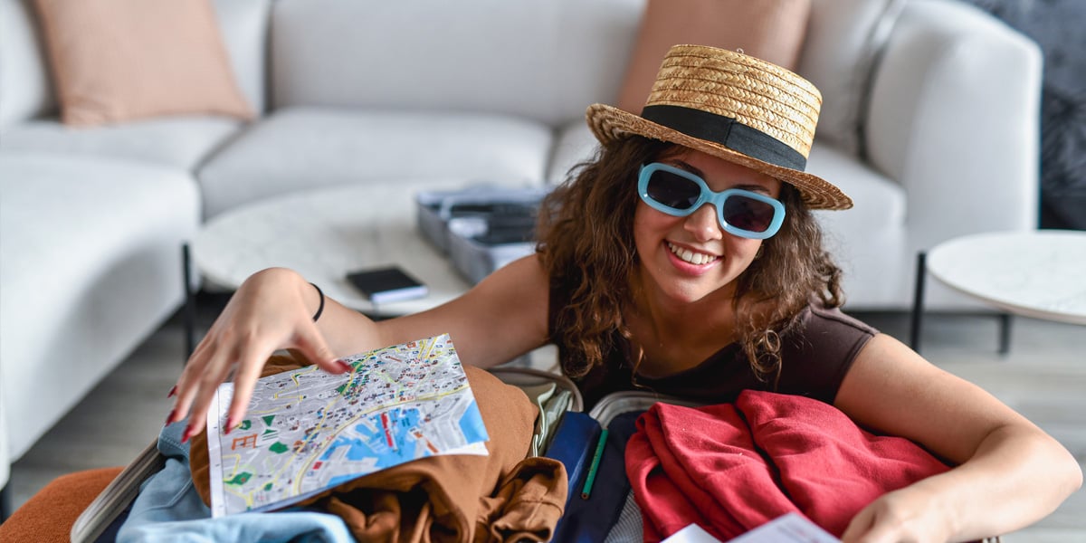 Woman wearing sunglasses and hat packing for vacation