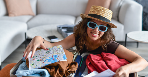 Woman with hat and sunglasses packing for vacation
